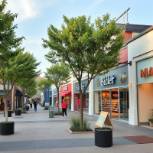 Vibrant outdoor shopping mall featuring popular stores like Zara and Apple.